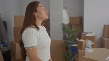 Yeni evdeki karton kutular arasında sessizce ve nazikçe nefes alan kadın, sükunet yardımı.
