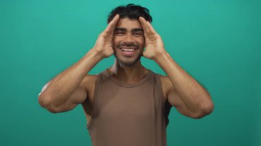 Stüdyoda elleri parlak yeşil arkaplan ile yüzünü kaplayan adam neşeli ifadeler yaparken; neşe.