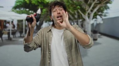 İspanyol bir adam sokakta elinde tornavidayla enerjik bir şekilde el kol hareketi yapıyor, bir şehir geçmişinde iletişim duygusu ve sönük bir coşku taşıyor..