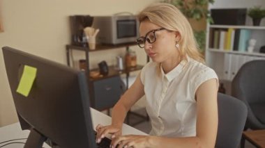 Genç sarışın kadın, bilgisayar klavyesindeki modern ofis binasında beyaz masanın üzerinde dinleniyor; yorgunluk.