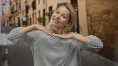 Kadın parmaklarıyla kalp hareketi yapıyor ve eski bir kasabada bir sokakta barış işareti tutuyor; mutluluk..