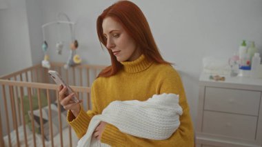 Sıcak yatak odasında beşiğiyle telefon kullanırken kucağında bir kadın, sıcak ev ortamında modern annelik temalarını sergiliyor..