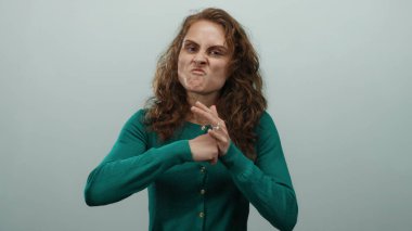 Öfkesini ifade eden bir kadın, beyaz arka plana karşı agresif bir tavırla hareket ediyor kıvırcık saçlı yeşil bir kazak giyiyor ve kafkas görünümlü izole bir ortamda hayal kırıklığını canlı bir şekilde tasvir ediyor.