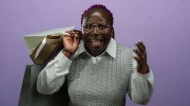 Elinde alışveriş torbalarıyla gülümseyen bir kadın mor arka planda neşeli bir ifade ve sürprizle..