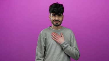 Gri kazaklı genç adam soyutlanmış pembe arka plana karşı duruyor. Samimi ve düşünceli görünüyor..