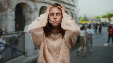 Roma Kolezyumu 'nun dışındaki kadın yoğun şehirde stresli görünüyor. Parlak bir günde kazak giyiyor..