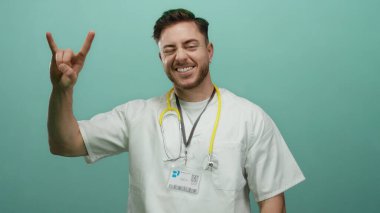 Steteskop takmış genç bir adam yeşil arka plana karşı el hareketi yapıyor. Sıradan ve dostane bir tavır sergiliyor..