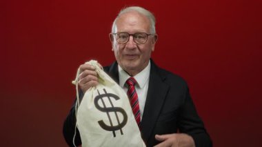 Kırmızı duvarda para çantası taşıyan kıdemli bir adam yozlaşmış iş anlaşmalarını simgeliyor..