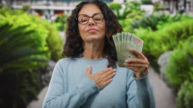 Bahçedeki kadın göğsünde Arjantin pezosu taşıyor. Açık havada gurur ve refahı simgeliyor..