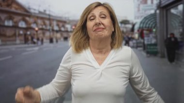 Kadın ayakta duruyor ve öğleden sonra güneşli şehir caddesinde el sallıyor; sosyal bağlantı sıcaklığı arkadaşlığı.