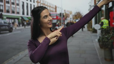 Kadın heyecan verici bir şekilde hareketli bir şehir caddesini işaret ediyor, canlı bir enerji ile, işaretler gösteriyor ve çevresindeki kentsel çevreyle meşgul oluyor..