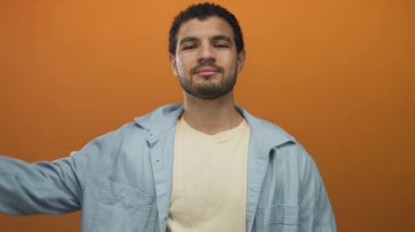 Mavi gömlekli genç adam elini kapatmış, gözleri turuncu stüdyoda saklanıyor. Gizlilik..