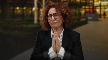 Kıvırcık saçlı ve gözlüklü bir kadın geceleri şehir sokaklarında el ele tutuşarak umudunu ve samimiyetini ifade ediyor..