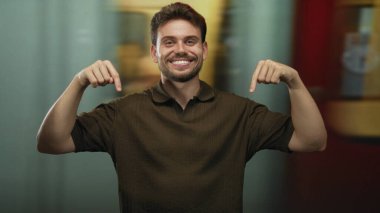 Adam her iki işaret parmağı aşağı tren istasyonu platformu, aşağıdaki uzaya gülümseme ve jest; dostça davet.