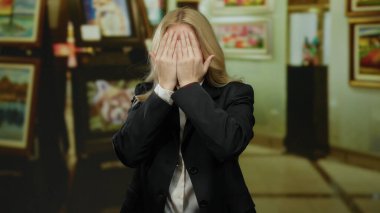 Galeride peekaboo oynayan sarışın kadın sanat dolu müze düzenine eğlenceli bir dokunuş katıyor..