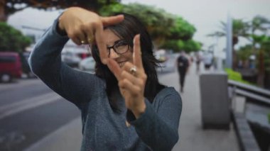 İşlek şehir caddesinde parmaklarını çerçeveleme jestinde tutan kadın, yaratıcı vizyon.