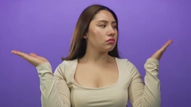 Ciddi ifadeleri olan genç İspanyol kadın mor stüdyoda avuçlarını açık tutuyor; belirsizlik seçim ikilemi.