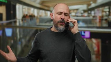 Kapalı bir alışveriş merkezinde hayal kırıklığına uğramış bir adam konuşuyor. Geçmişi bulanık, sakalı, kel ve günlük kıyafetleri acil durum ve iş anlayışını iletiyor..