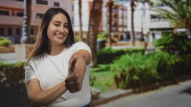 Kadın gülümseyen ve başparmak kaldıran bina önünde ve palmiye ağaçları, beyaz gömlek giyiyor diğer çerçeveler çapraz kollar; iyimserlik.