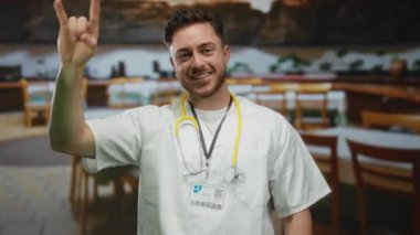 Genç bir adam, sakallı bir doktor, steteskopla şehir terasında gülümsüyor, açık havada şehir, tıbbi ve dinamik bir restoran ortamında sıradan titreşimler sergiliyor..