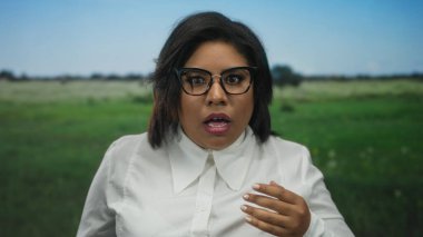 Park yerinde, şaşırmış bir ifade, gözlük, beyaz gömlek, arka plan, duygusal tepki, genç yetişkin, açık hava, yeşil çimen, şaşkın görünüyor.