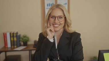 Ofisteki kadın kendine güvenen gözlüklü ve takım elbiseli sarı saçlı, kitaplı ve arka planda bitki yetiştiren modern ve profesyonel bir atmosfer yaratıyor..