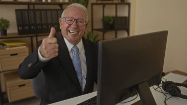 Takım elbiseli son sınıf öğrencisi, ofisteki bilgisayarda onaylıyor. Profesyonel iş ortamında güven ve memnuniyet gösteriyor..