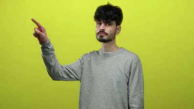 Gri kazaklı genç İspanyol adam izole edilmiş sarı arka planda odaklanma ve dikkat kavramı gösteriyor.