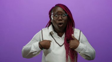 Örgülü bir kadın, kendini mor bir arkaplan üzerinde belirterek etkileyici jestler ve gözlüklerle, şaşkınlık ve merakını dile getiriyor..