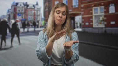 Tuğla binanın önündeki işlek bir caddede avuçlarını açıp para isteyen genç sarışın bir kadın..