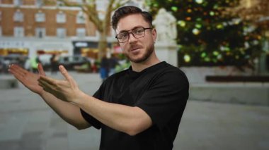 Arka planda bulanık insanlar ve dükkanlar olan bir caddede uzanmış elleri olan genç sakallı bir adam, şehir ve cazip bir senaryoyu canlandırıyor..