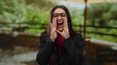 Genç İspanyol kadın yemyeşil bir açık hava parkında neşeyle bağırıyor, canlı enerji ve heyecanı vurguluyor..