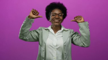 Kendine güvenen bir kadın, pembe bir arka plana, gözlüklü, gri ceketli, kendine güvenen ve profesyonelce davranan bir kadına dikkat çekiyor..