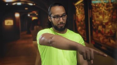 Bir adam, galeri koridorundaki bir tabloya uzanan koluyla işaret ediyor. Meraklanma..