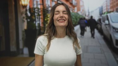 Kadın şehir caddesinde yumruklarını kaldırmış ve parmaklarını birbirine yaklaştırmış olarak orta parmağını gösteriyor..