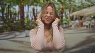 Bir kadın sokakta çok geniş bir gülümseme ile yanaklarından yumruklarını sıkar; sevinç heyecanı mutluluk coşkusu.