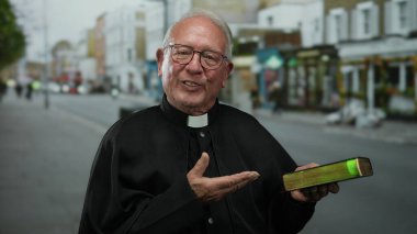 Başrahip elinde bir İncil tutuyor, bir şehir caddesinde sıcak bir şekilde gülümsüyor, açık şehir ortamına olan inancını iletiyor, ruhani rehberlik için geleneksel siyah bir rahip kıyafeti giyiyor..