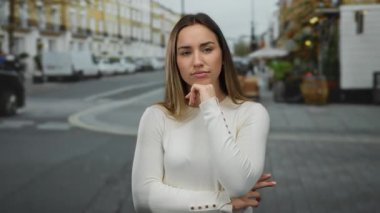 Düşünceli bir ifadeyle, şehrin arka planında, sonbaharda açık havada günlük hayatı tasvir eden bir kadın.