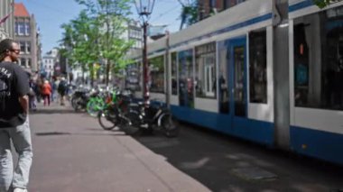 Amsterdam, Hollanda 'da tramvayın yanından geçen, bisiklet, şehir sokakları ve şehir yaşamını gösteren bulanık manzaralı insanlar..