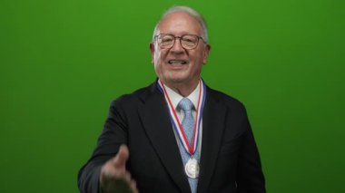 Gümüş madalyalı kıdemli bir adam yeşil bir geçmişe karşı gülümsüyor. Başarı ve profesyonelliği aktarıyor..