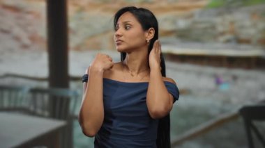 Sahil kenarında şık elbiseler içinde sakin bir ifade ve sakin bir ortam içinde sakin bir sahil manzarası sergileyen bir kadın..