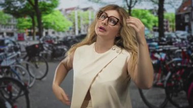 Sarışın, gözlüklü, alnında gözlüklü, bisiklet parkında bisiklet parkında duran kolsuz, üstsüz bir kadın..