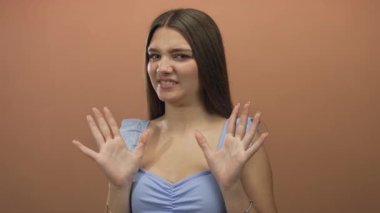 Surat asan ve el ele tutuşan genç bir kız stüdyoda kameraya bakan açık mavi bluz giyen, iç huzursuzluğu olan bir kız..