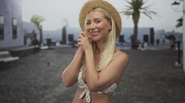 Beyaz binanın önündeki güneşli bir caddede görünen dekoltesi olan bir kadın el çırpıyor; bayram neşesi.