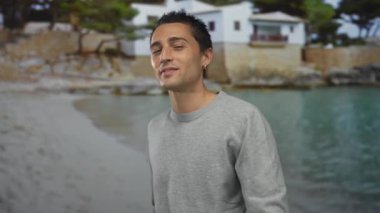 Kol saatli genç İspanyol adam sıcak güneş ışığı altında kumlu sahilde bir öpücük yolluyor..