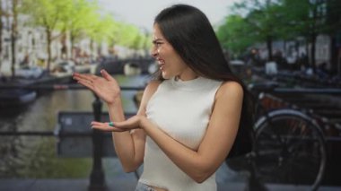 Kanal yakınındaki bir sokakta parmak gösteren İspanyol kadın ve şehir manzarasında kapalı gözlerle yüzünü buruşturan tiksinti..