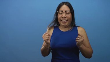 Yumruklarını sıkmış, gözleri kapalı gülümseyen ve stüdyoda esinti yapan bir kadın, sevinç kutlamaları yapıyor..