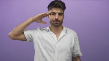 Beyaz gömlekli İspanyol adam mor bir stüdyoda el ele tutuşarak ciddi bakışlarla selam veriyor; saygı.