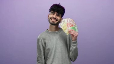 Gülümseyen adam Norveç kronu banknotlarını mor arka planda tutarak modern İskandinav ortamında zenginliği ve refahı sembolize ediyor..