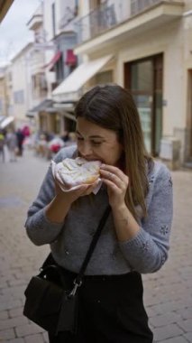 Eski şehrin sevimli bir caddesinde geleneksel hamur işiyle eğlenen bir kadın genç ve neşeli bir atmosferle canlı bir açık deniz manzarası yakalıyor..